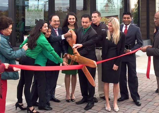 Narender Taneja, Bennigan'™s of Fremont franchise owner, and Anschul Taneja, Bennigan'™s of Fremont managing director, from left, cut a red ribbon with oversized wooden scissors Wednesday at the grand opening of the new Bennigan'™s restaurant at Pacific Commons in Fremont. Behind Anschul Taneja is Paul Mangiamele, Legendary Restaurant Brands chairman and chief executive officer. Photo courtesy of Bennigan'™s of Fremont